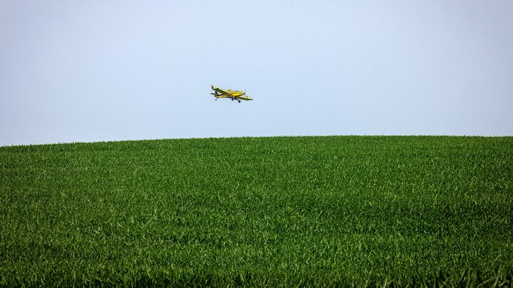 Plane spraying field with pesticide. 